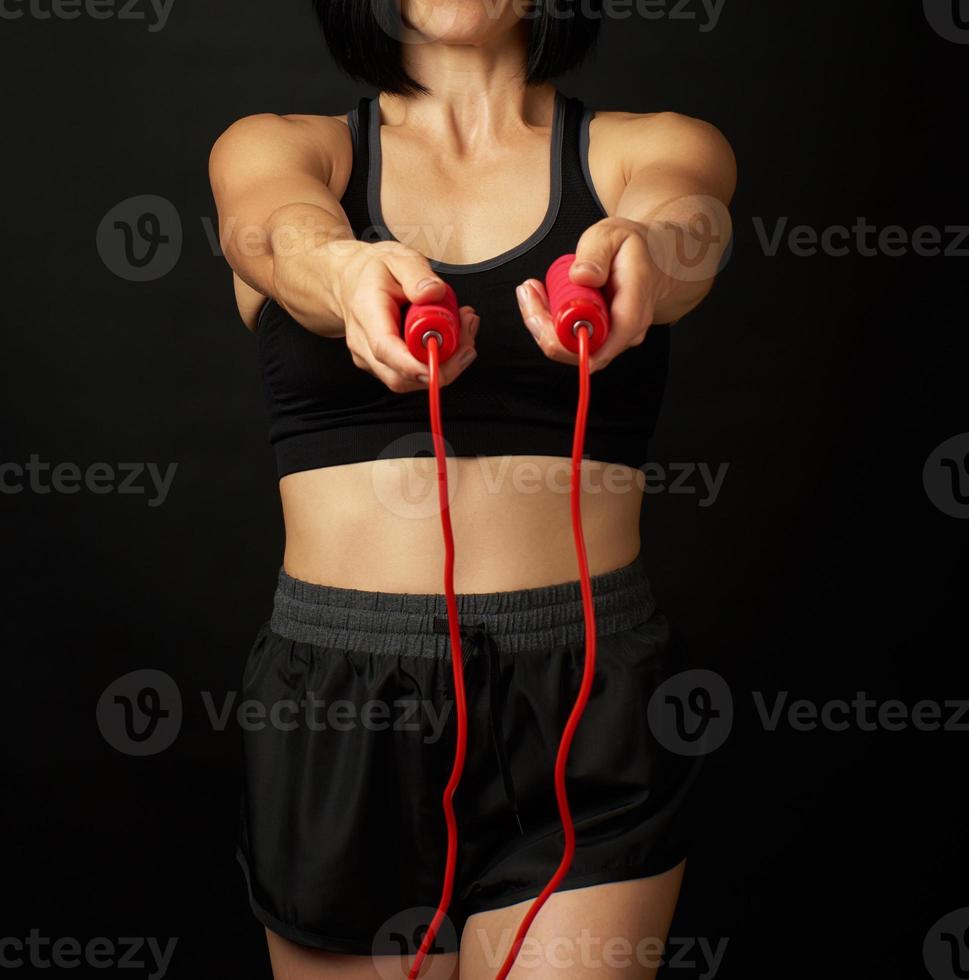 young woman with a sports figure in black uniform holds a red rope for jumping photo