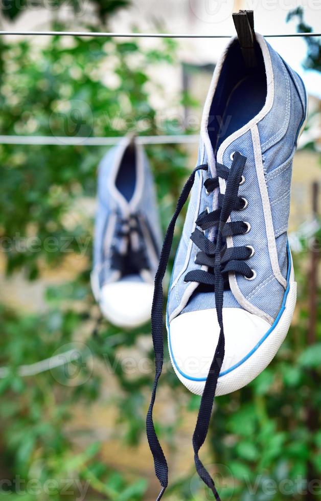 old blue sneaker hanging on a rope behind a wooden clothespin photo