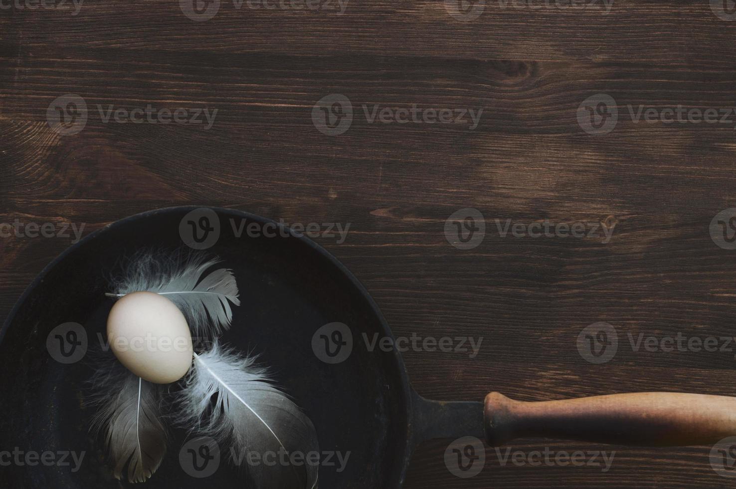 Raw chicken egg in a black cast-iron frying pan photo