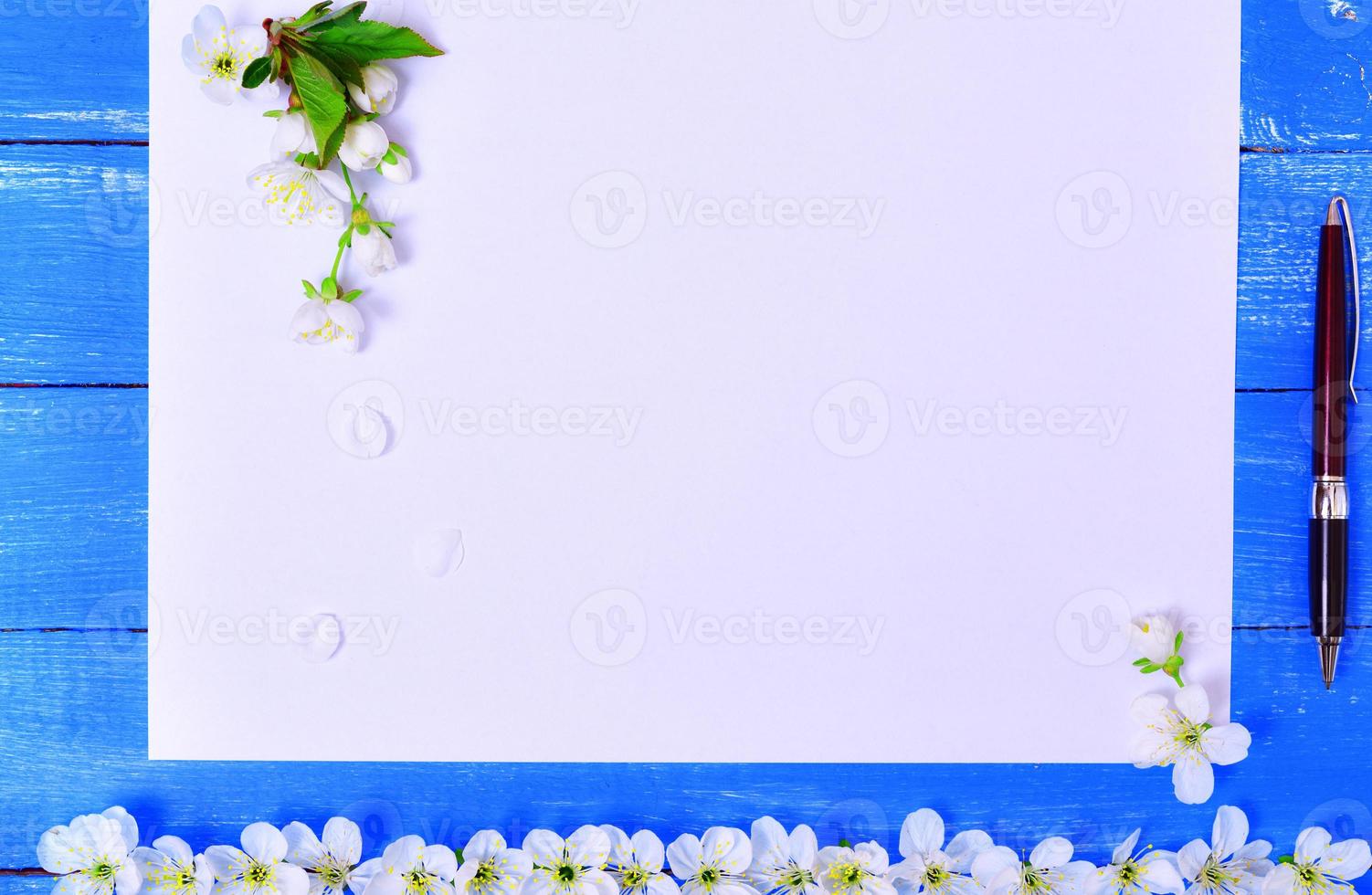 White blank sheet with a writing pen on a blue wooden surface photo
