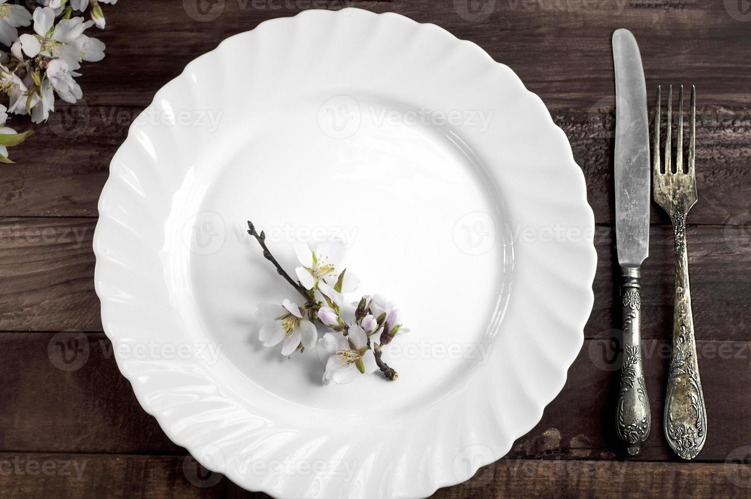 White dish with iron cutlery on a brown wooden surface photo