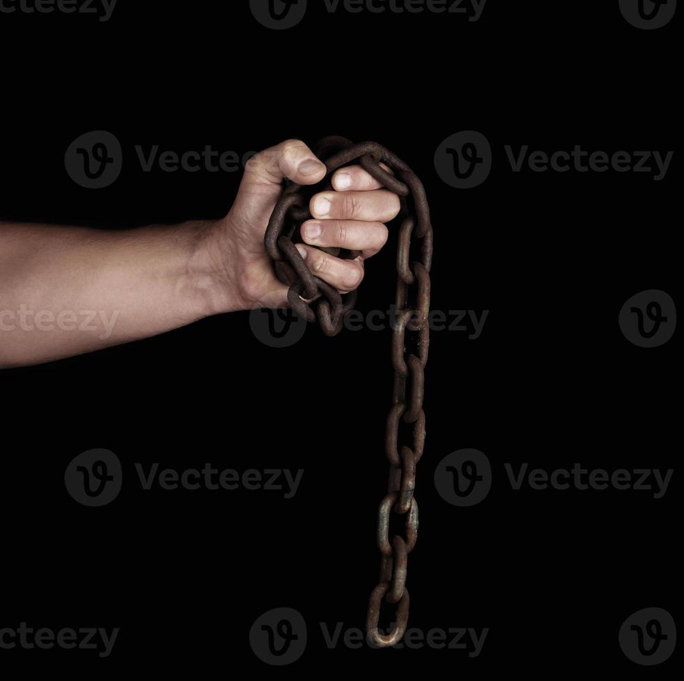 adult man in black clothes holds a brown rusty chain in his hand photo