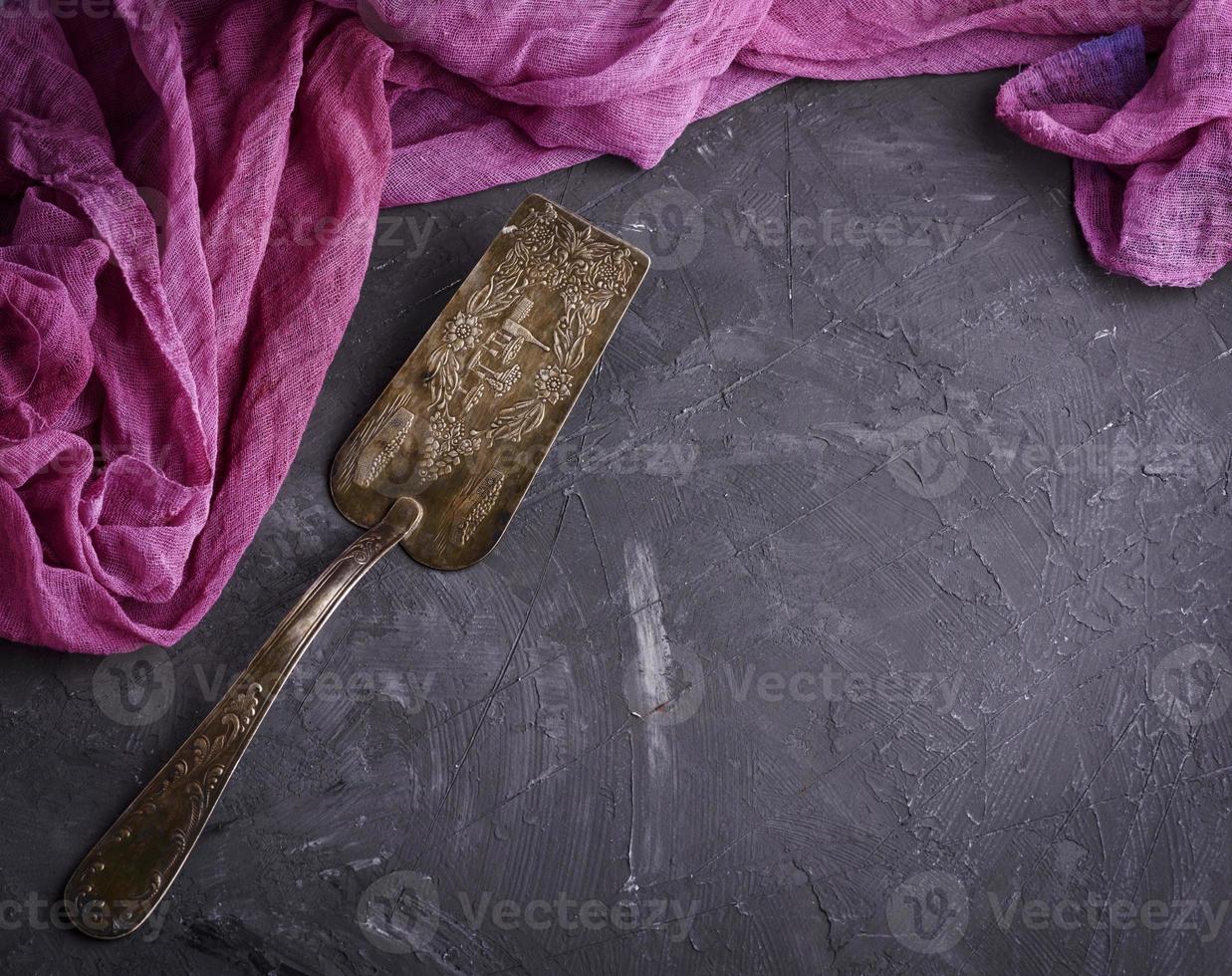 vintage iron spatula for dessert on a black surface photo