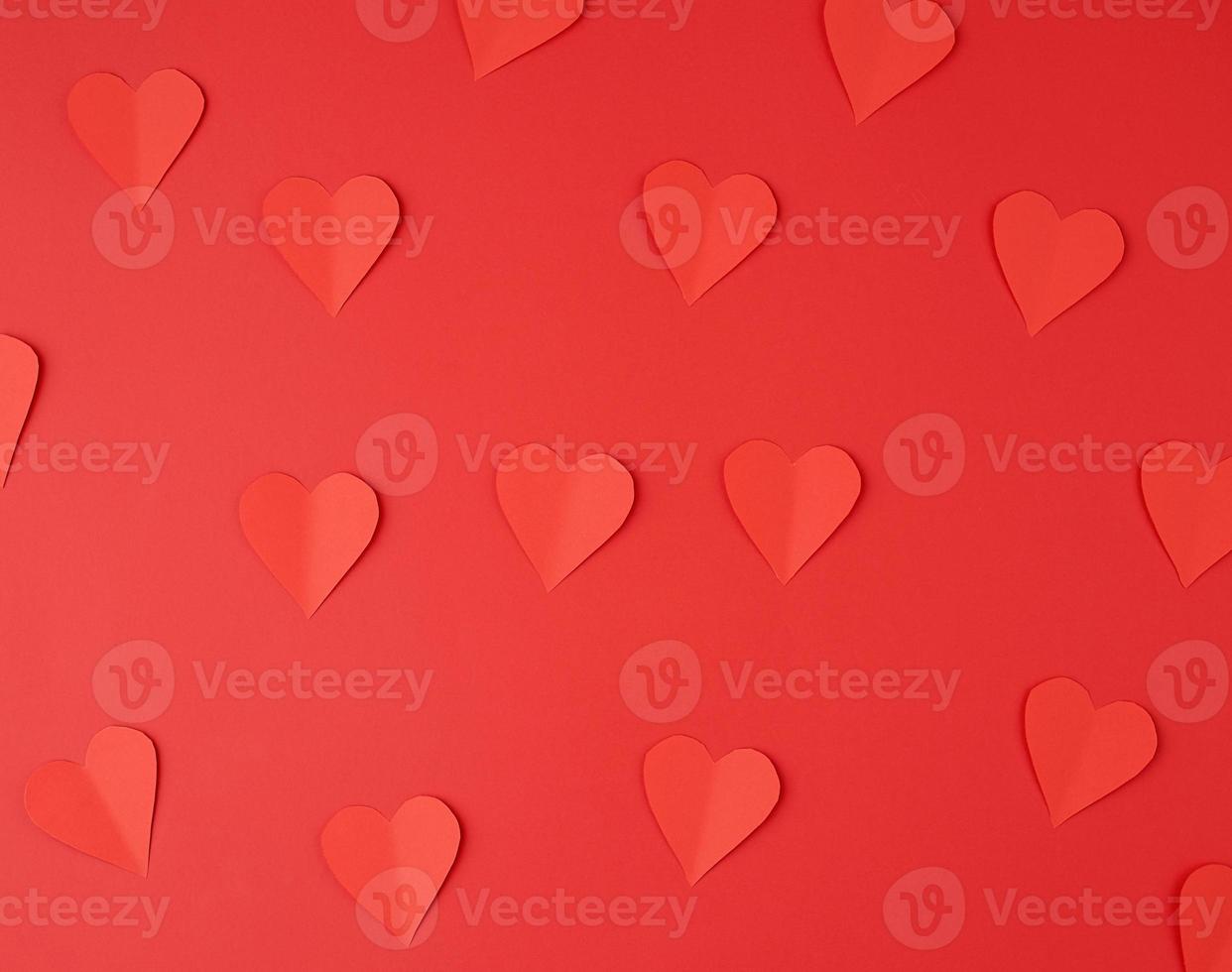 hearts cut out of red paper on a red background, festive backdrop for Valentine's Day photo