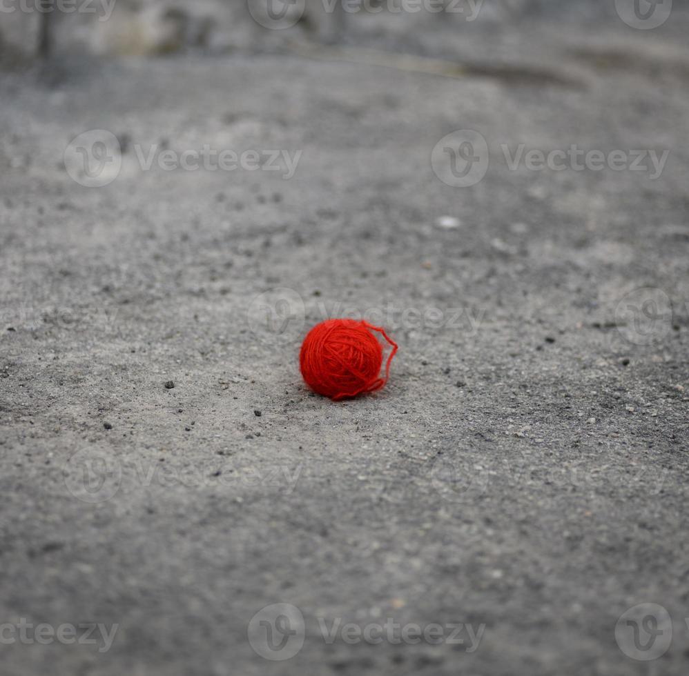 red woolen ball lies on the gray asphalt photo