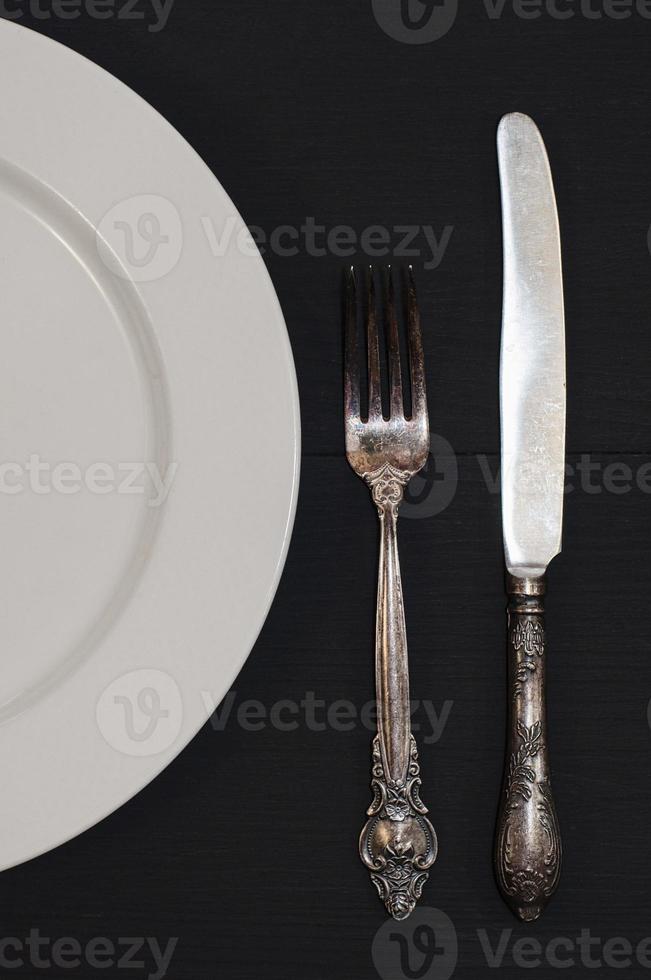 Half empty white plates, vintage knife and fork on  table photo