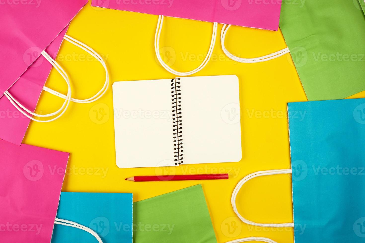 open notebook with blank white sheets and multi-colored paper shopping bags photo