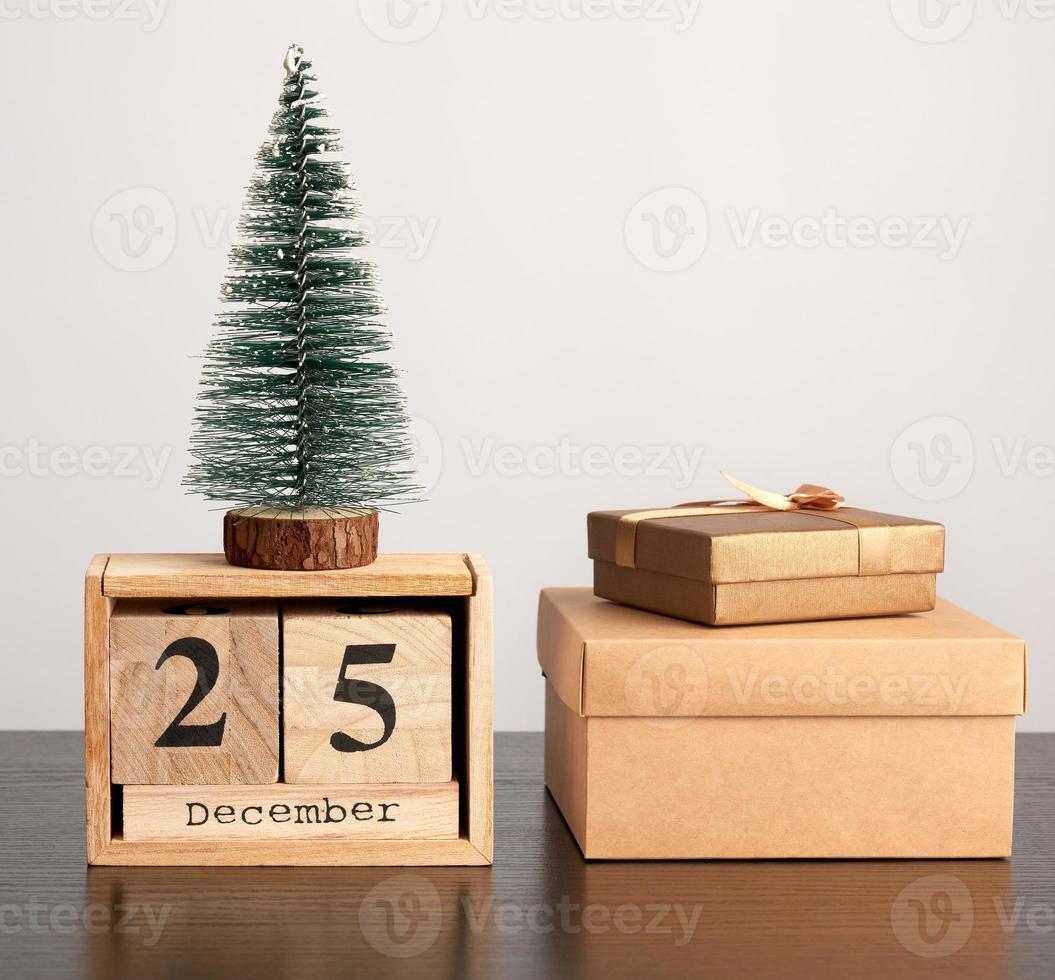 calendario retro de madera de bloques, árbol decorativo de navidad y cajas de cartón con regalos foto