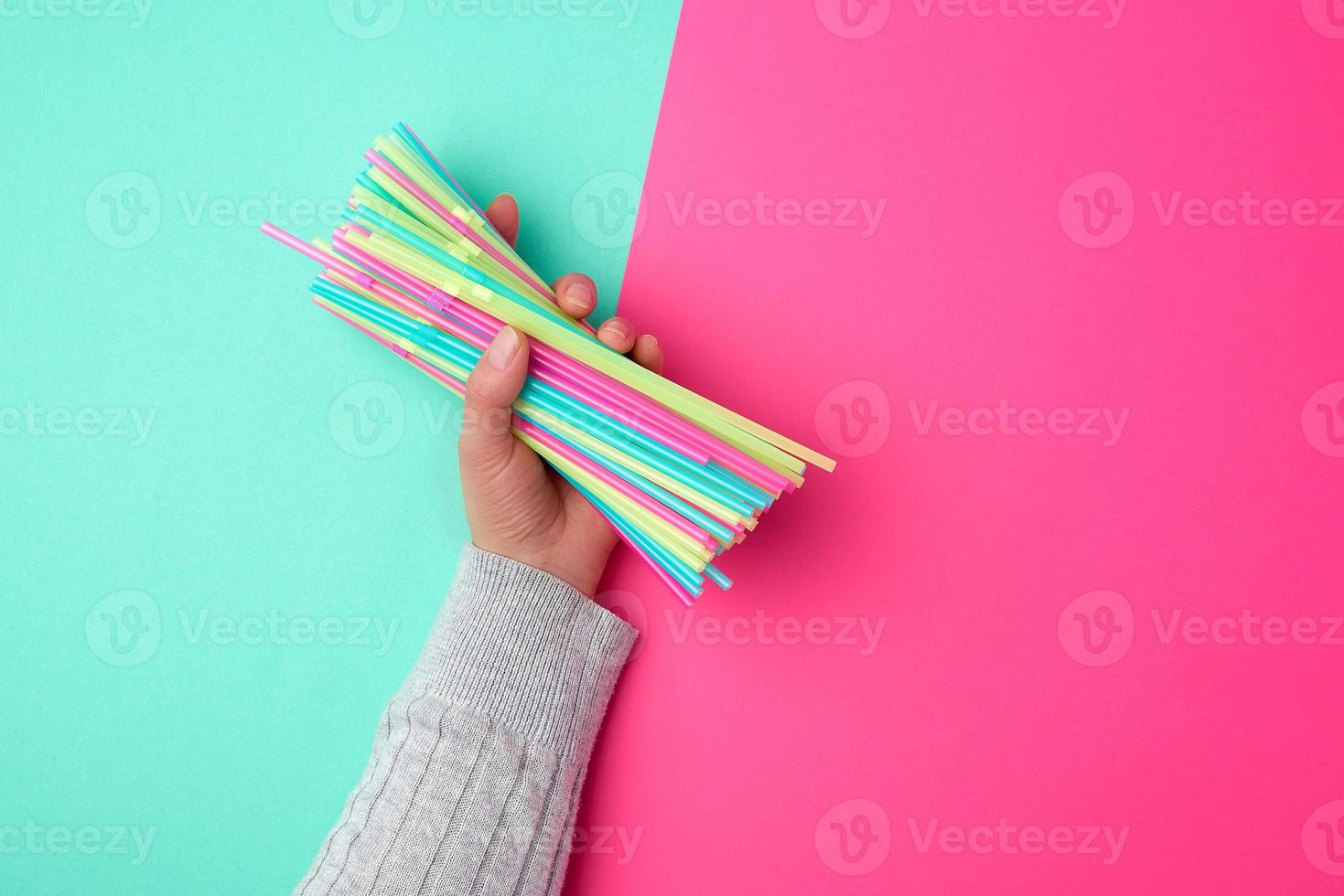 female hand holding multicolored plastic cocktail tubes photo