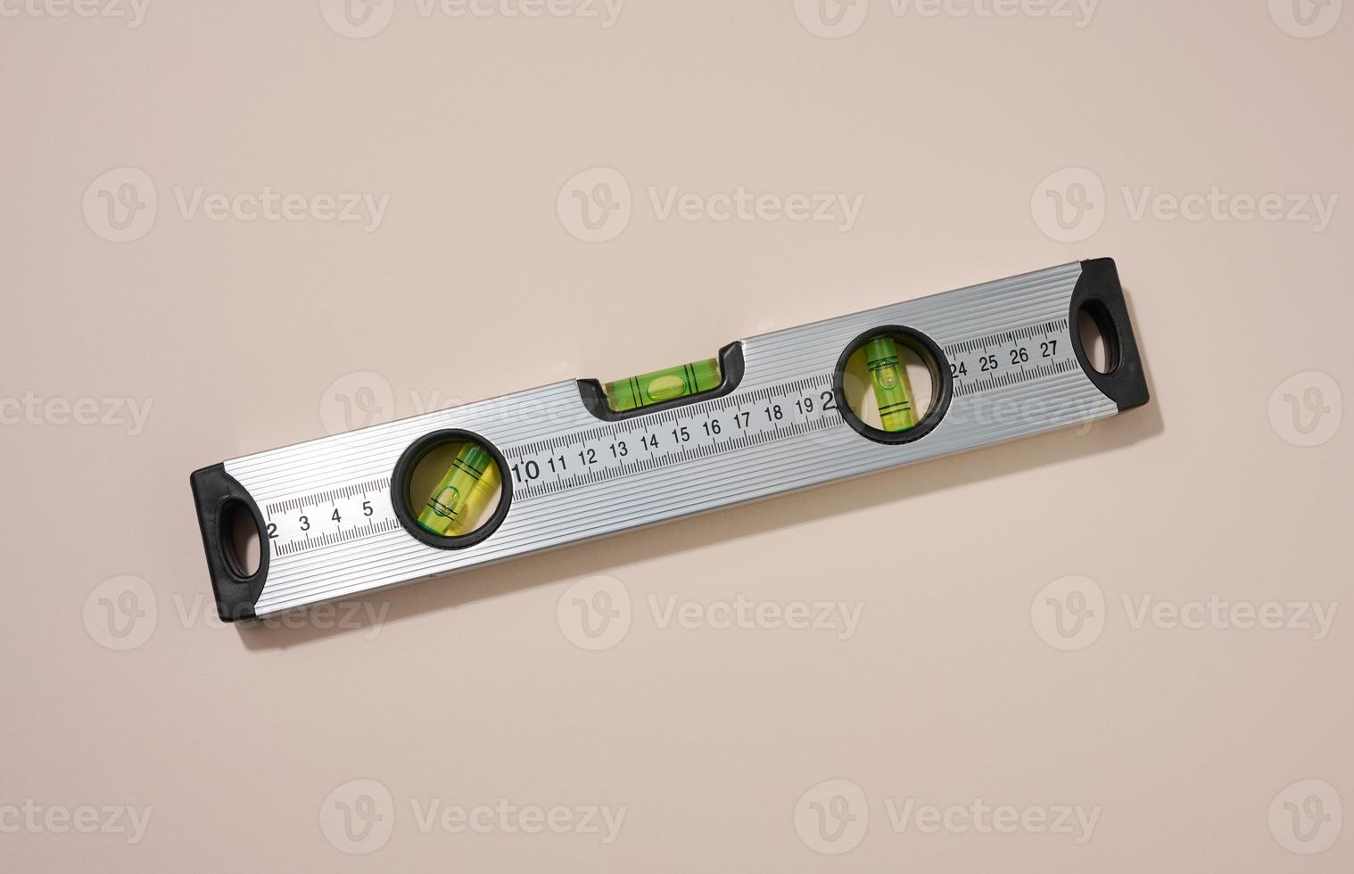 metallic building level on a beige background. Measuring instrument photo