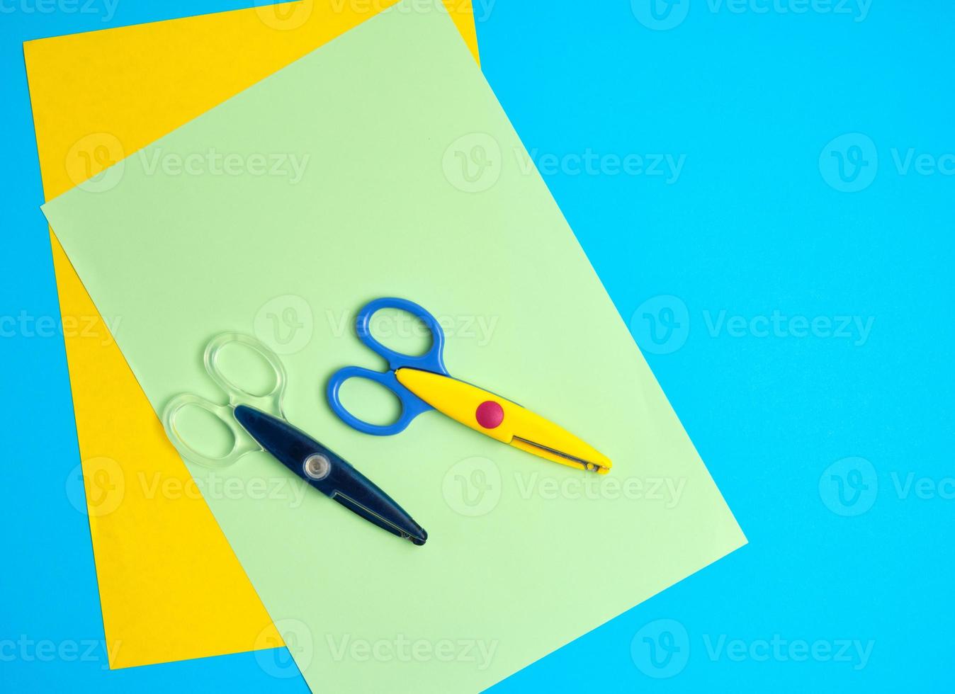 pair of plastic scissors and colored paper on a blue background photo