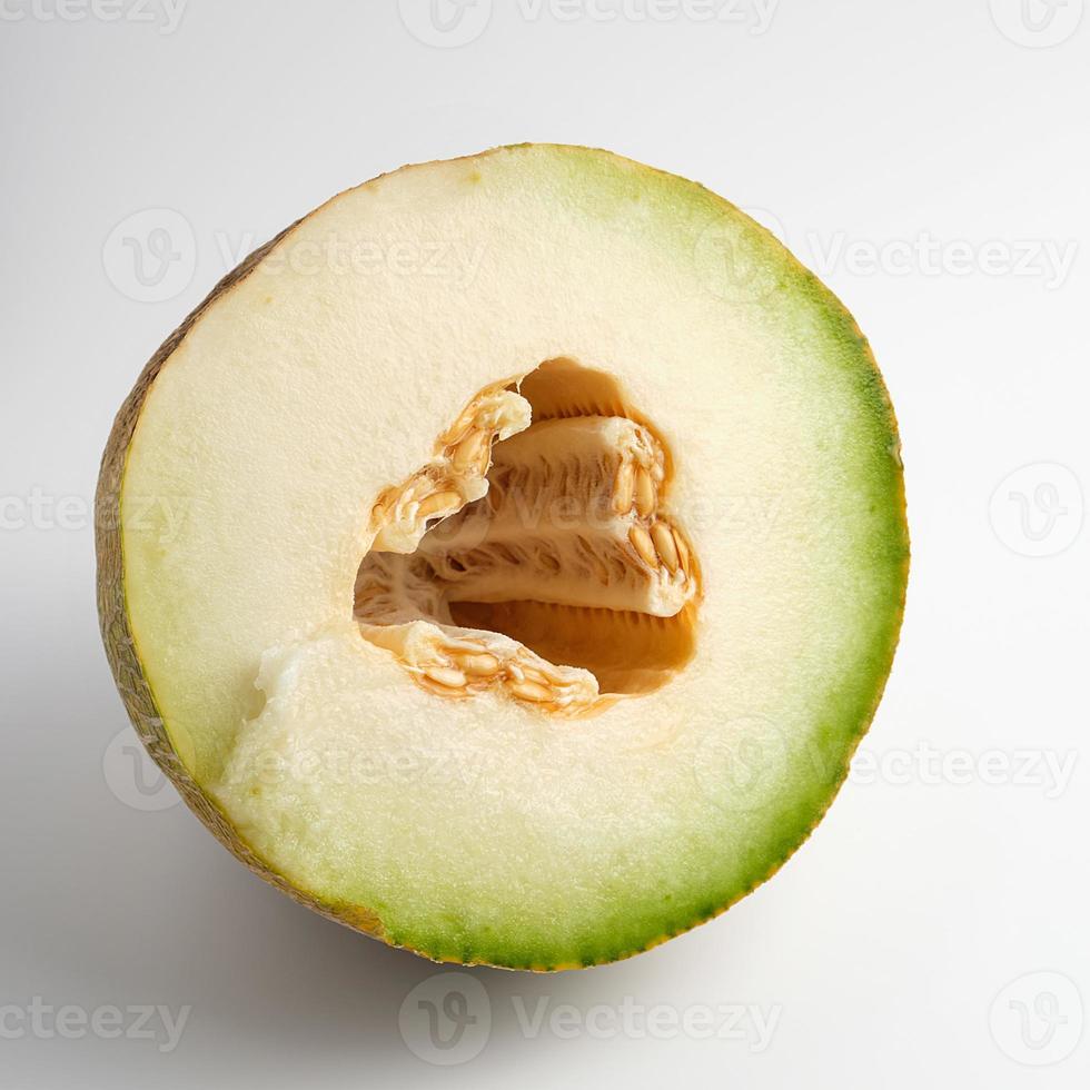 half of ripe yellow melon with seeds on white background photo