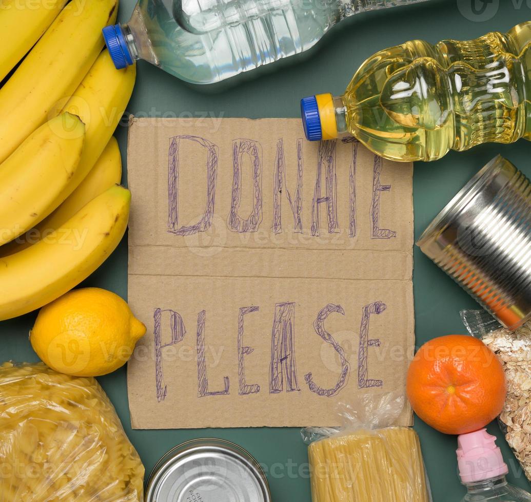 inscription on the cardboard please donate various products. Fresh fruits, pasta and canned food photo