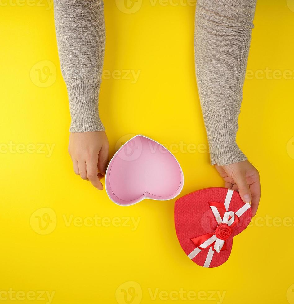 two female hands holding an open red heart-shaped box, festive backdrop photo