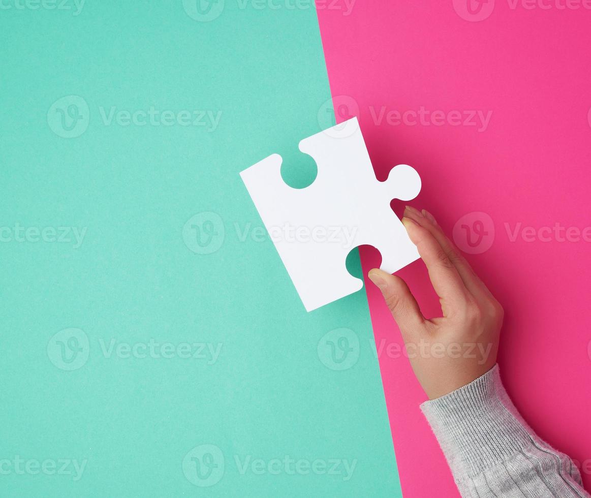 la mano femenina sostiene un gran rompecabezas blanco vacío sobre un fondo colorido foto