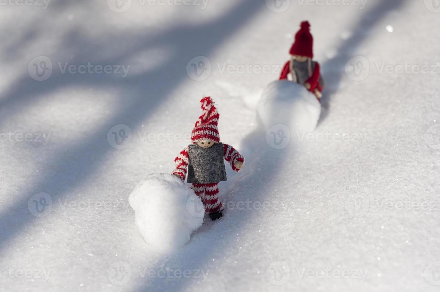 dos hombres de juguete con bolas de nieve rodaron montañas cubiertas de nieve foto