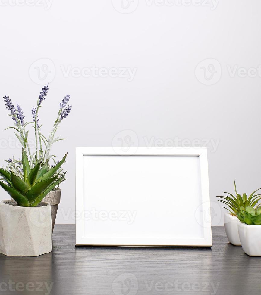 empty white frame, flowerpot with flower on a black table photo