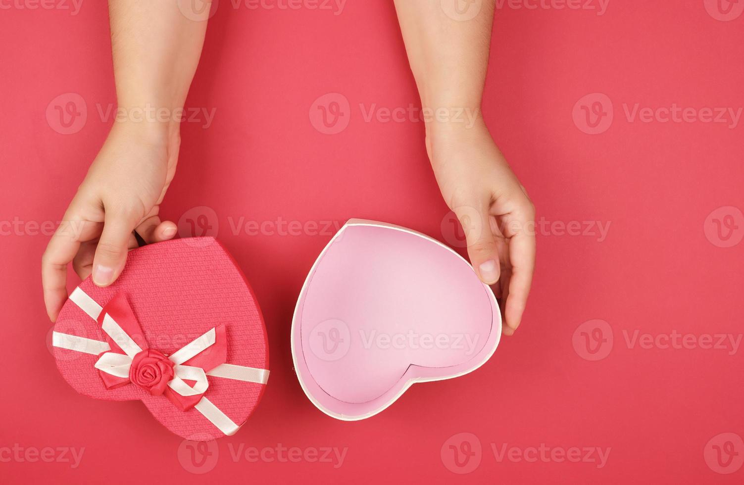 two hands hold a paper open red box in the shape of a heart photo