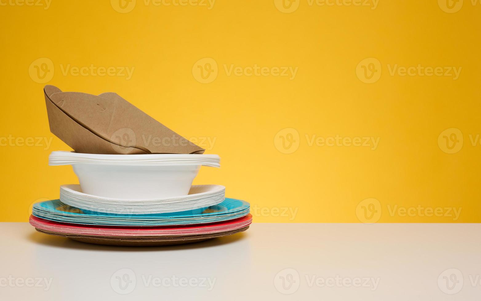 Stack of disposable paper plates on yellow background photo