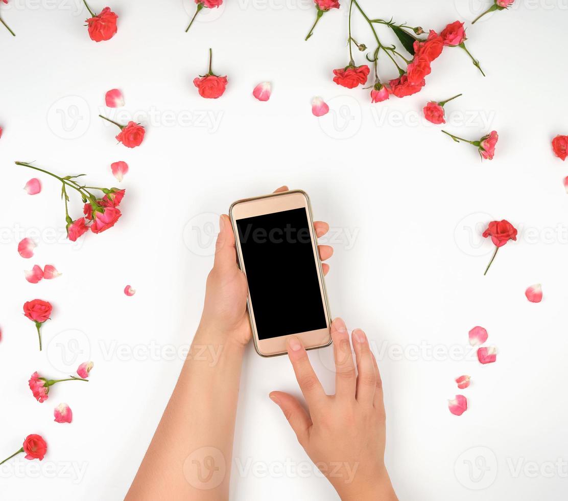 dos manos femeninas sostienen un teléfono inteligente con una pantalla negra en blanco foto