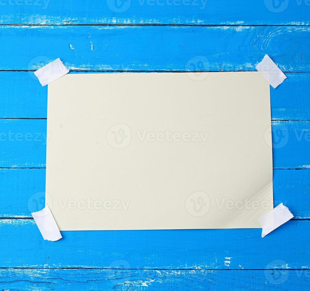 A4 blank white sheet attached with adhesive tape to a blue wooden surface photo