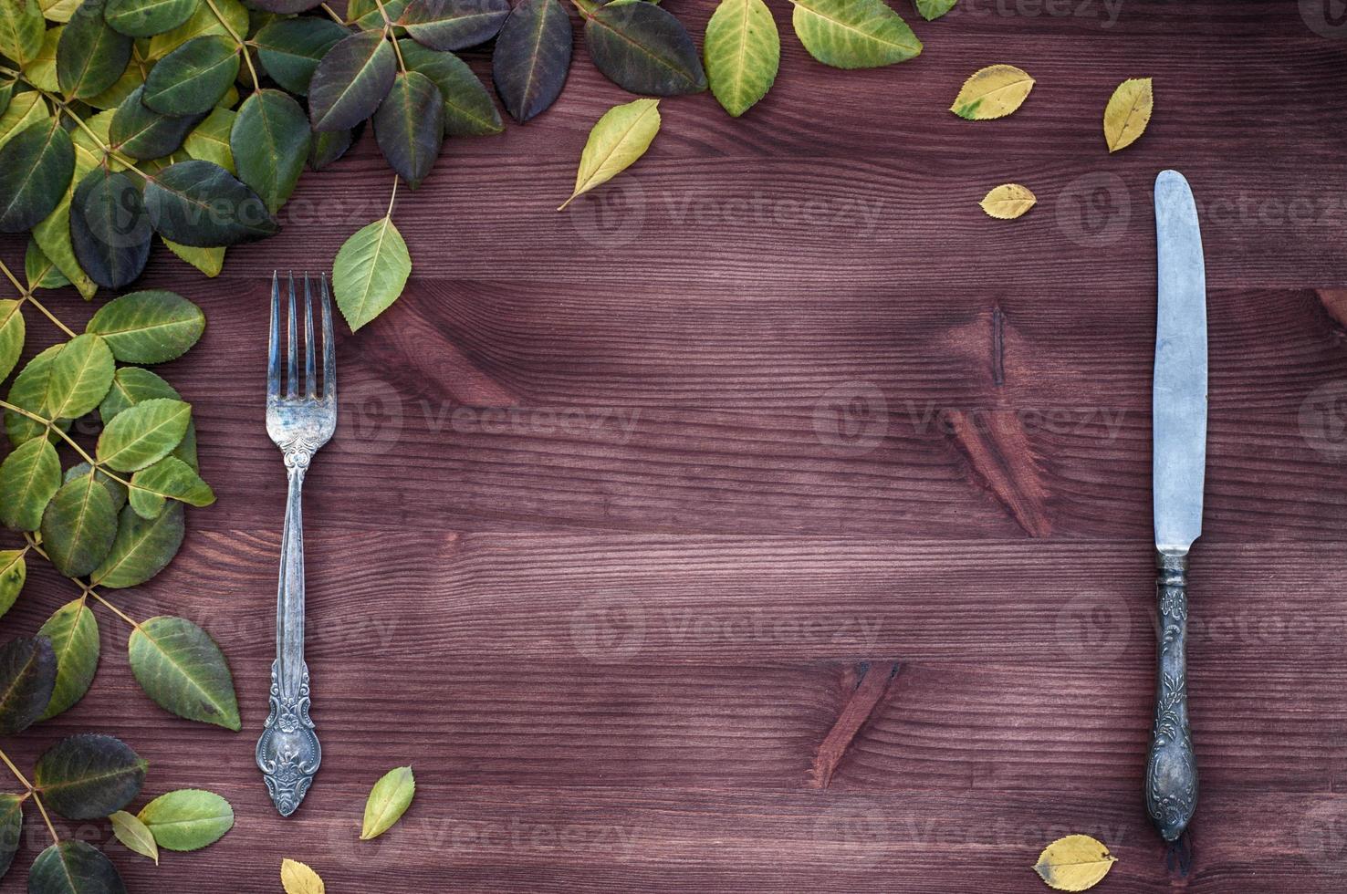 Knife and fork on a brown wooden surface, empty space photo