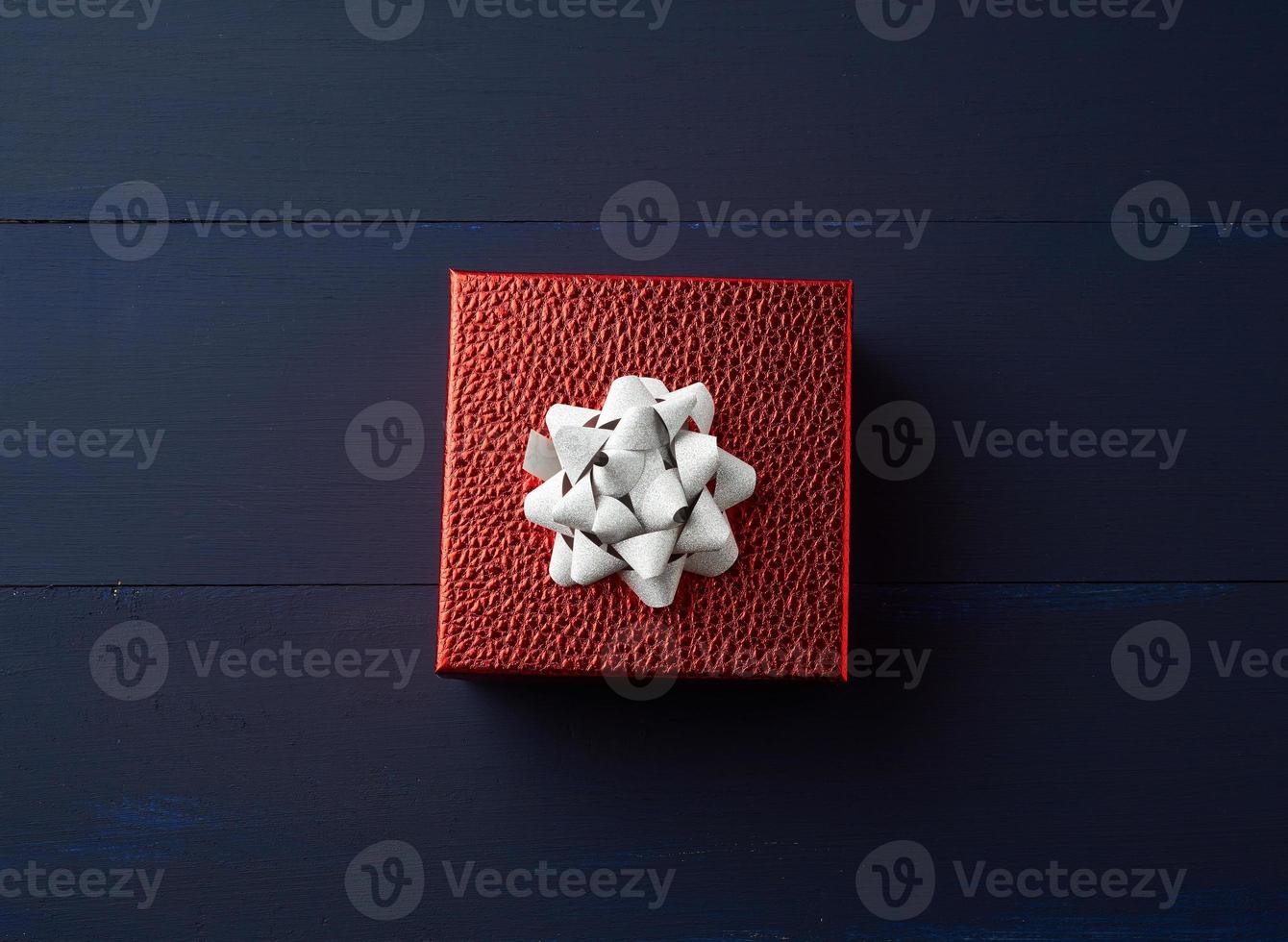 square red box tied with a golden ribbon, concept of congratulations and gifts photo