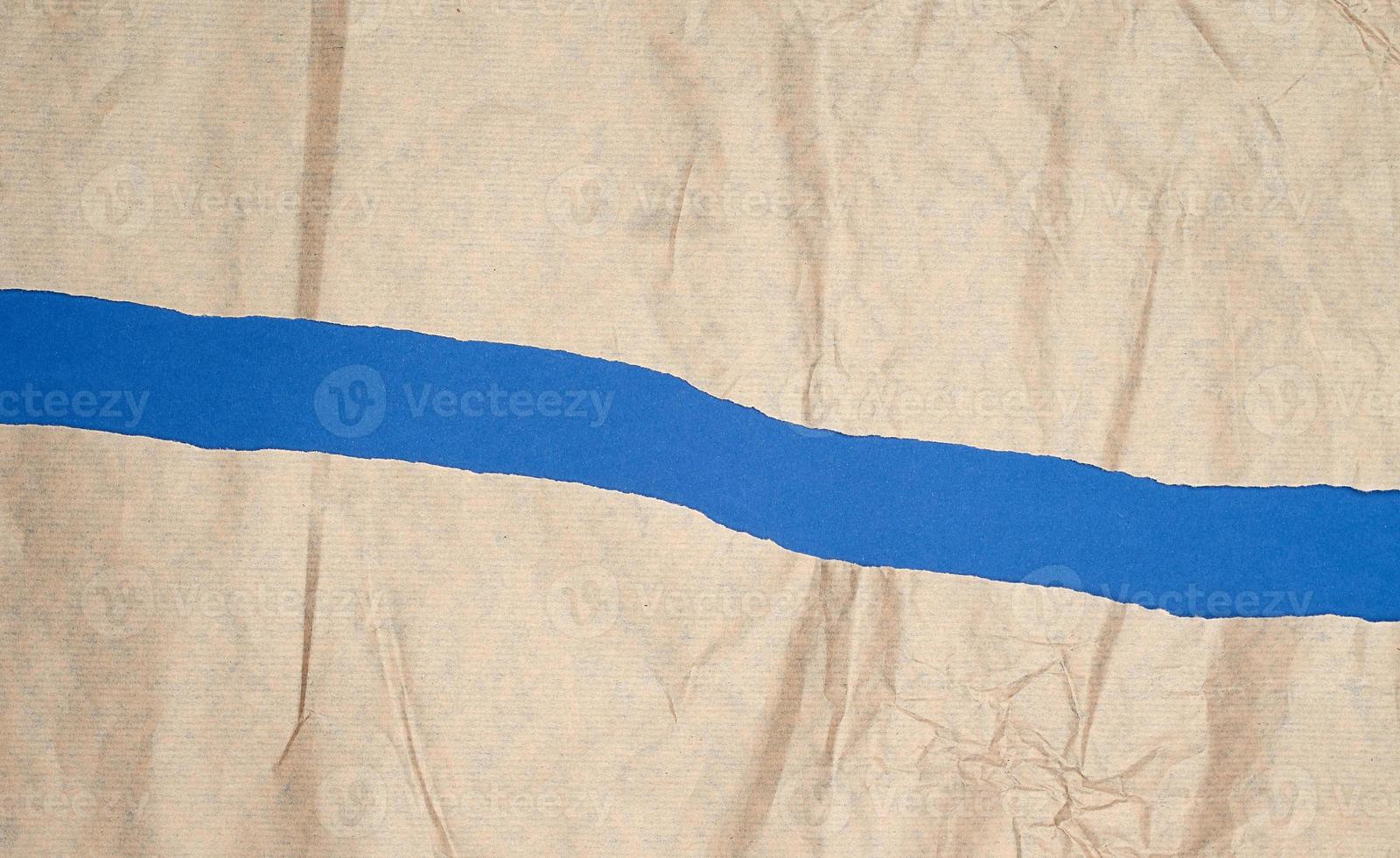 torn brown sheet of paper on a blue background, full frame photo