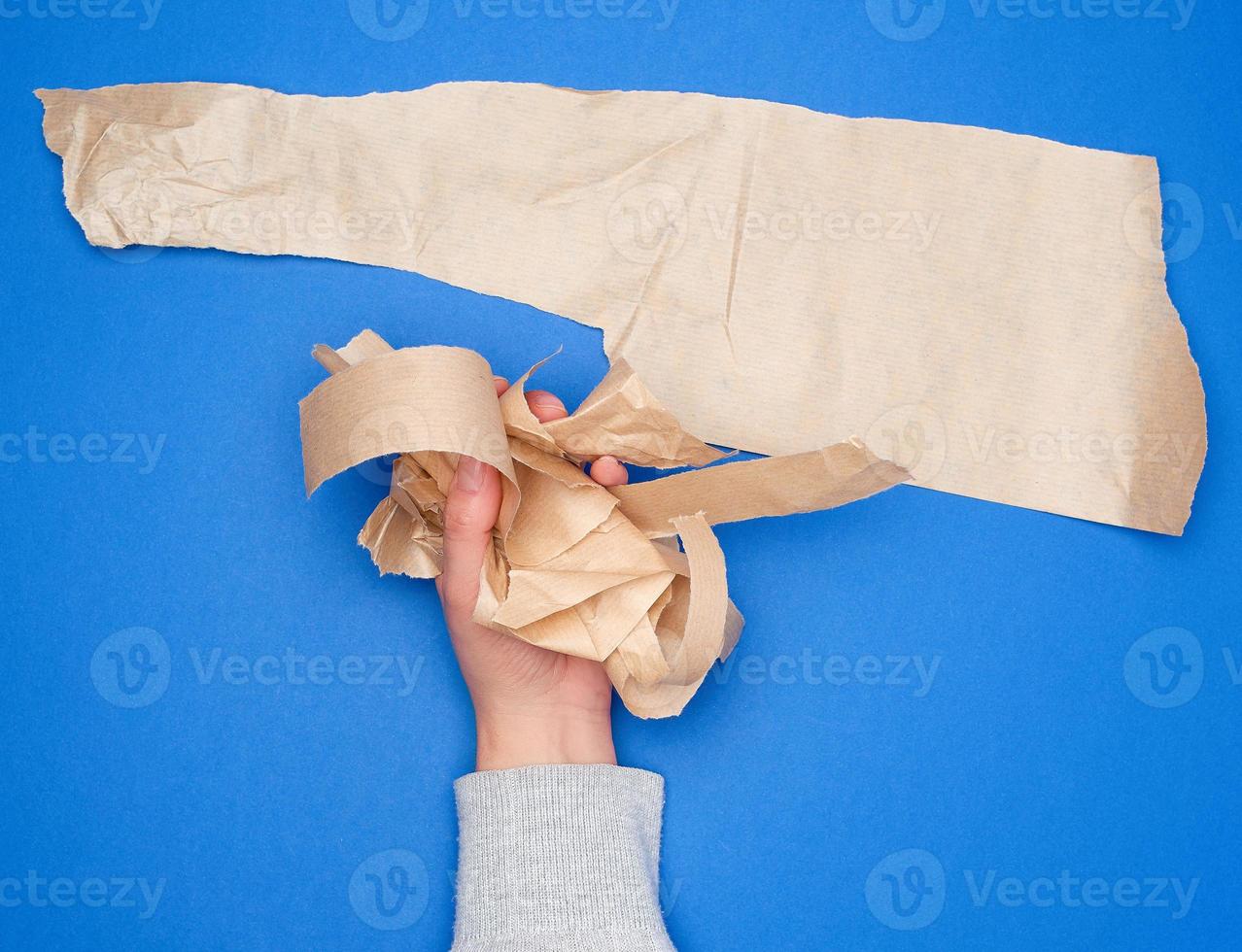 hand holds crumpled pieces of brown parchment paper photo
