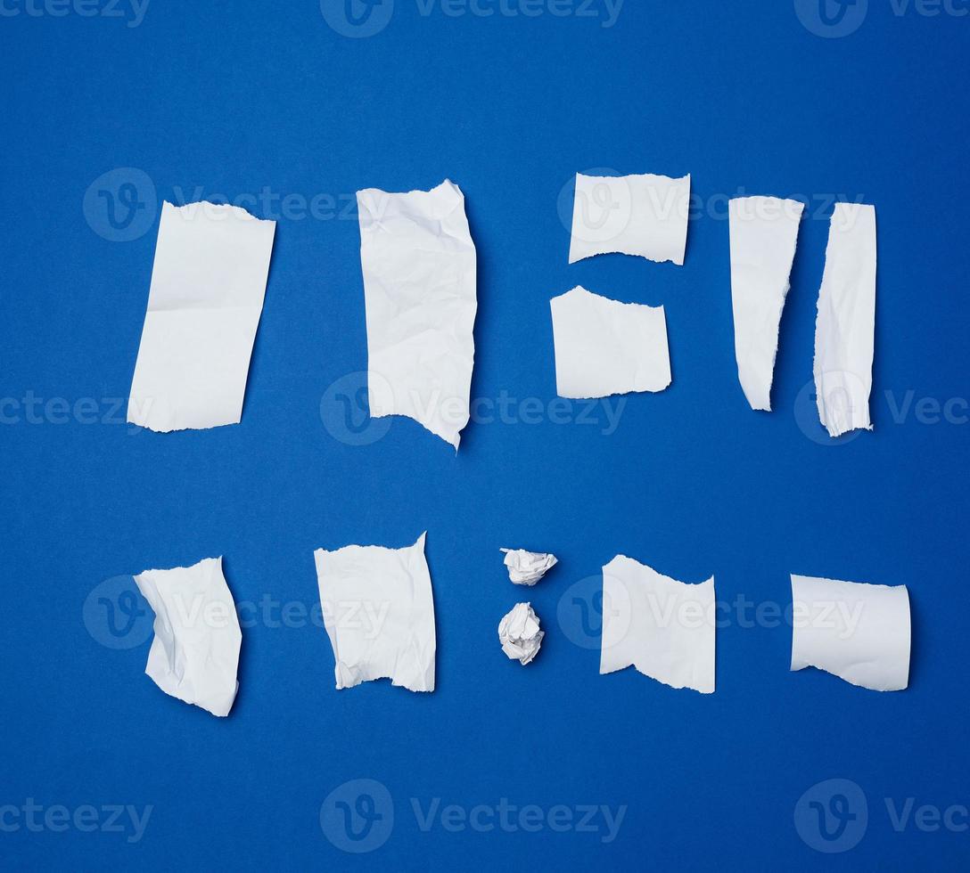 set of various pieces of torn white crumpled paper on a blue background photo