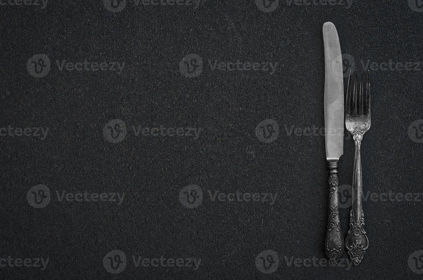 Silver fork and knife on the black surface photo