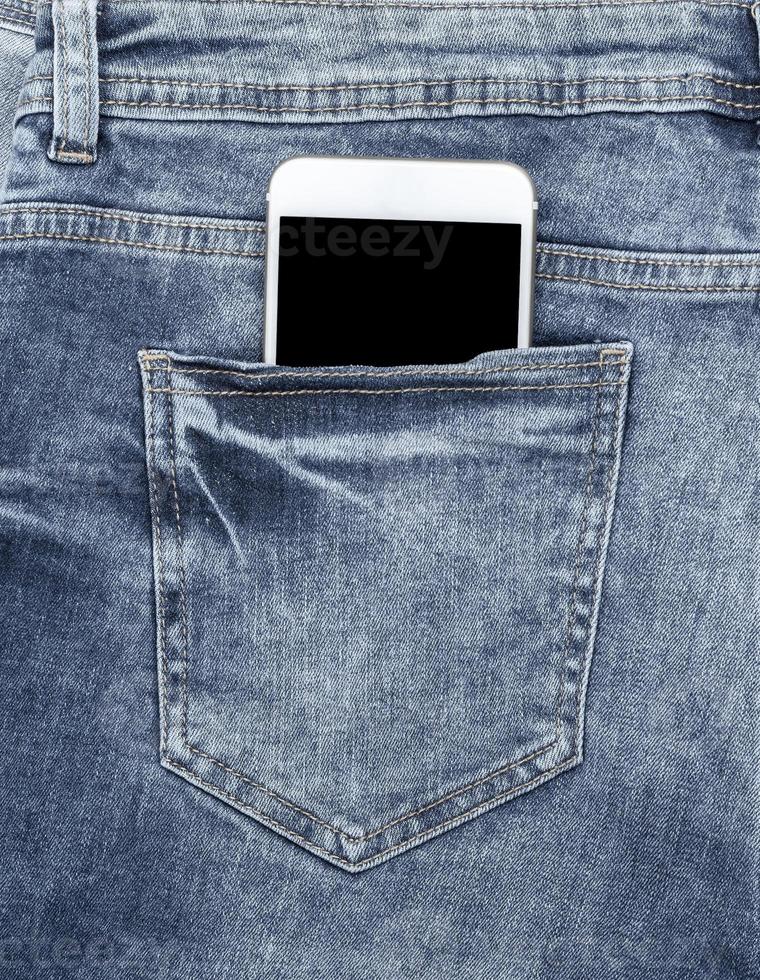 teléfono inteligente blanco en el bolsillo trasero de los jeans azules foto