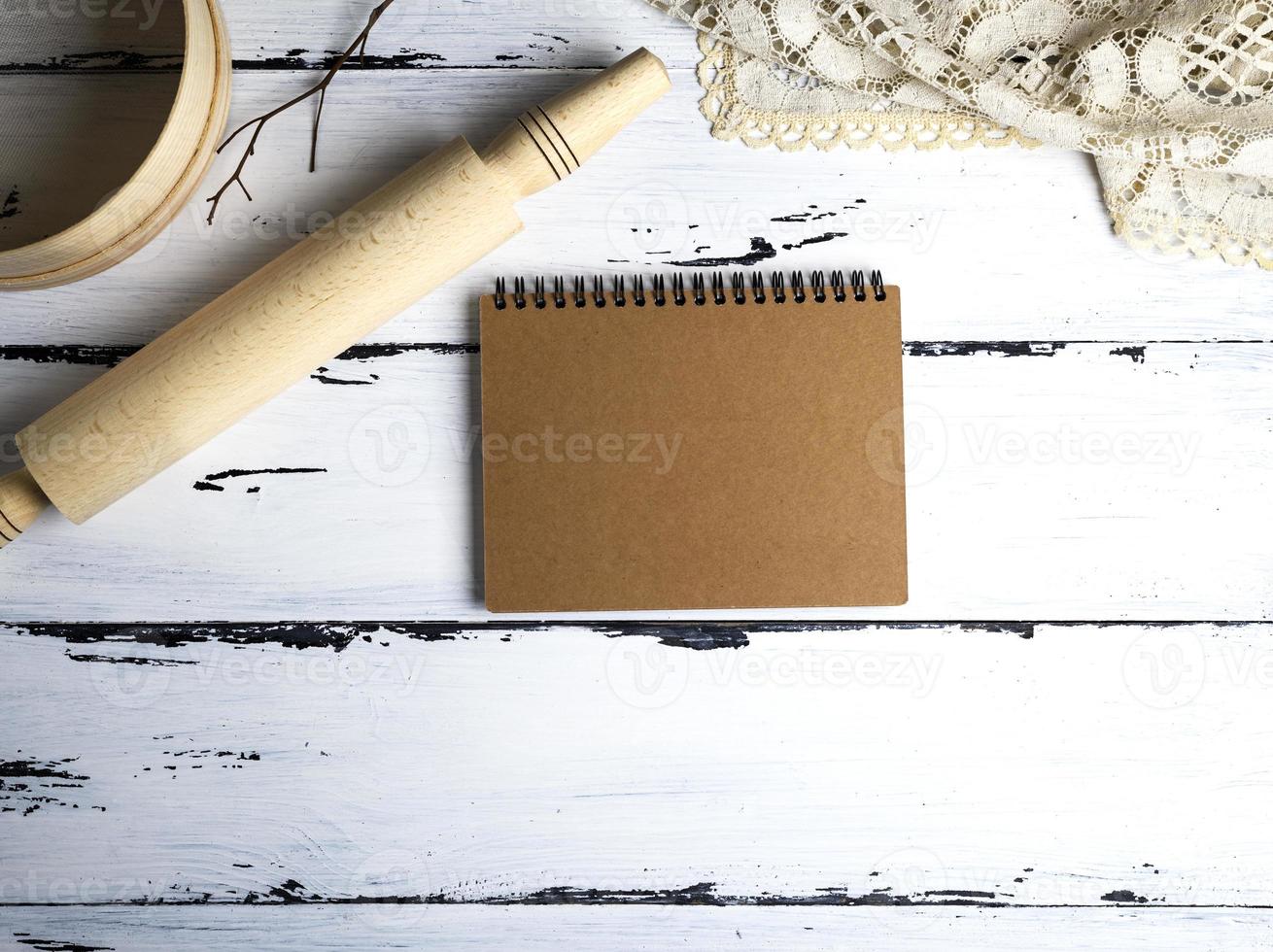 empty paper notepad, wooden rolling pin and a sieve photo