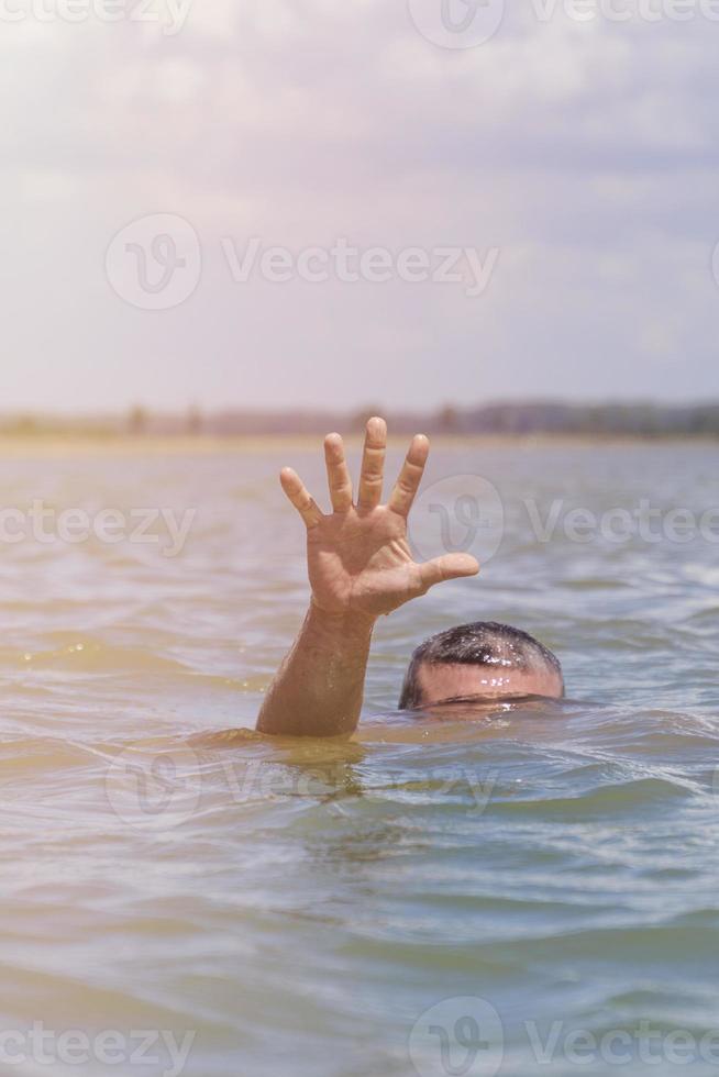 right man's hand gives a signal for help out of the water photo