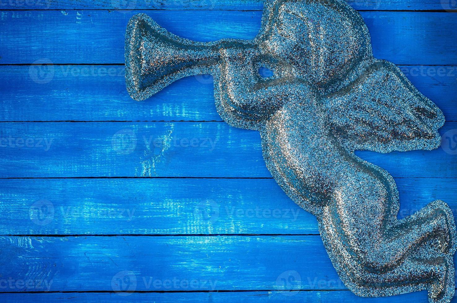 Figure angel of shiny particles on a blue wooden background photo