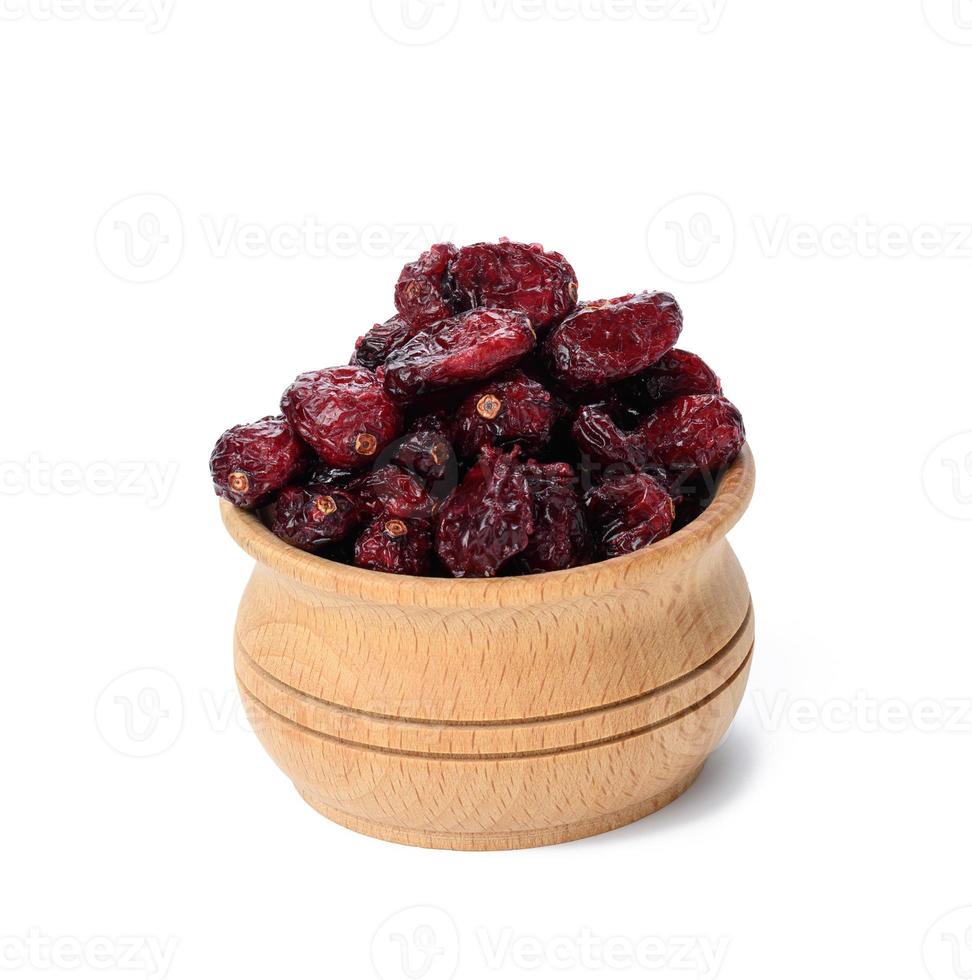 a bunch of dried cranberries in a wooden bowl on a white background. Delicious berry photo