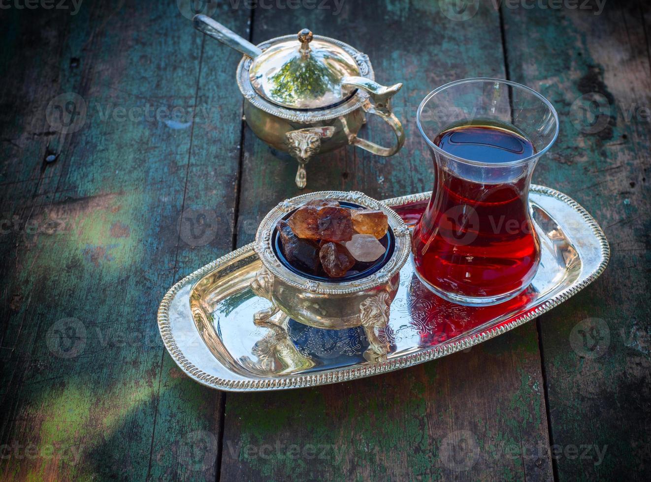 Black tea Turkish glass with slices of sugar on a silver platter, photo