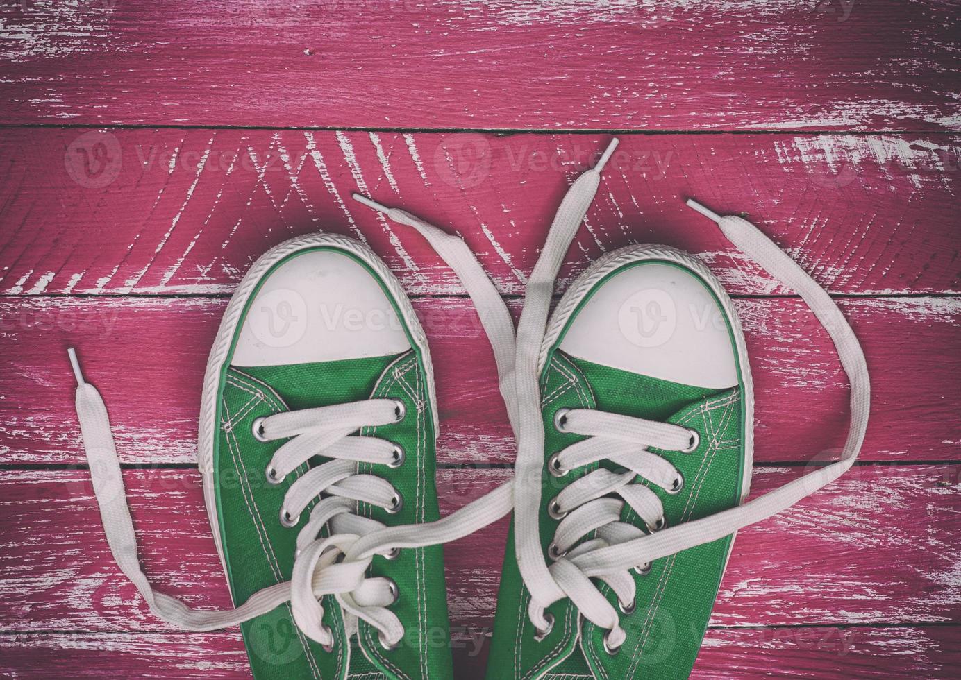 pair of worn sneakers on a pink green old wooden surface photo