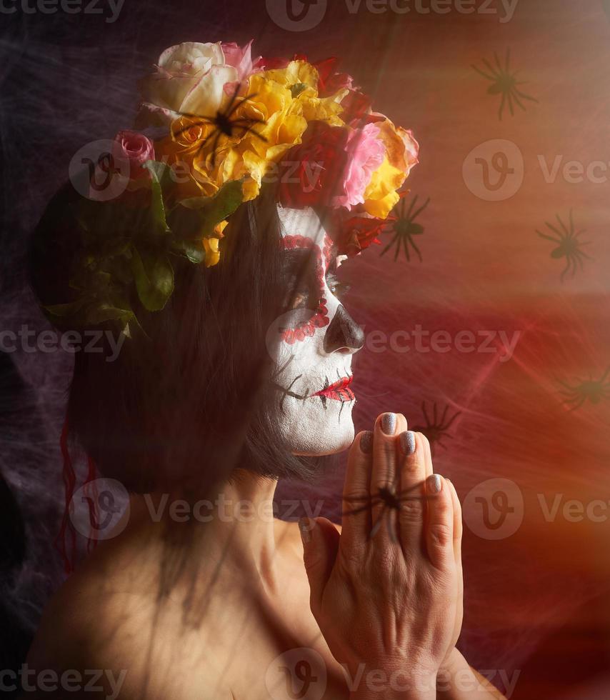 girl with black hair is dressed in a wreath of multi-colored roses and makeup is made on her face Sugar skull photo