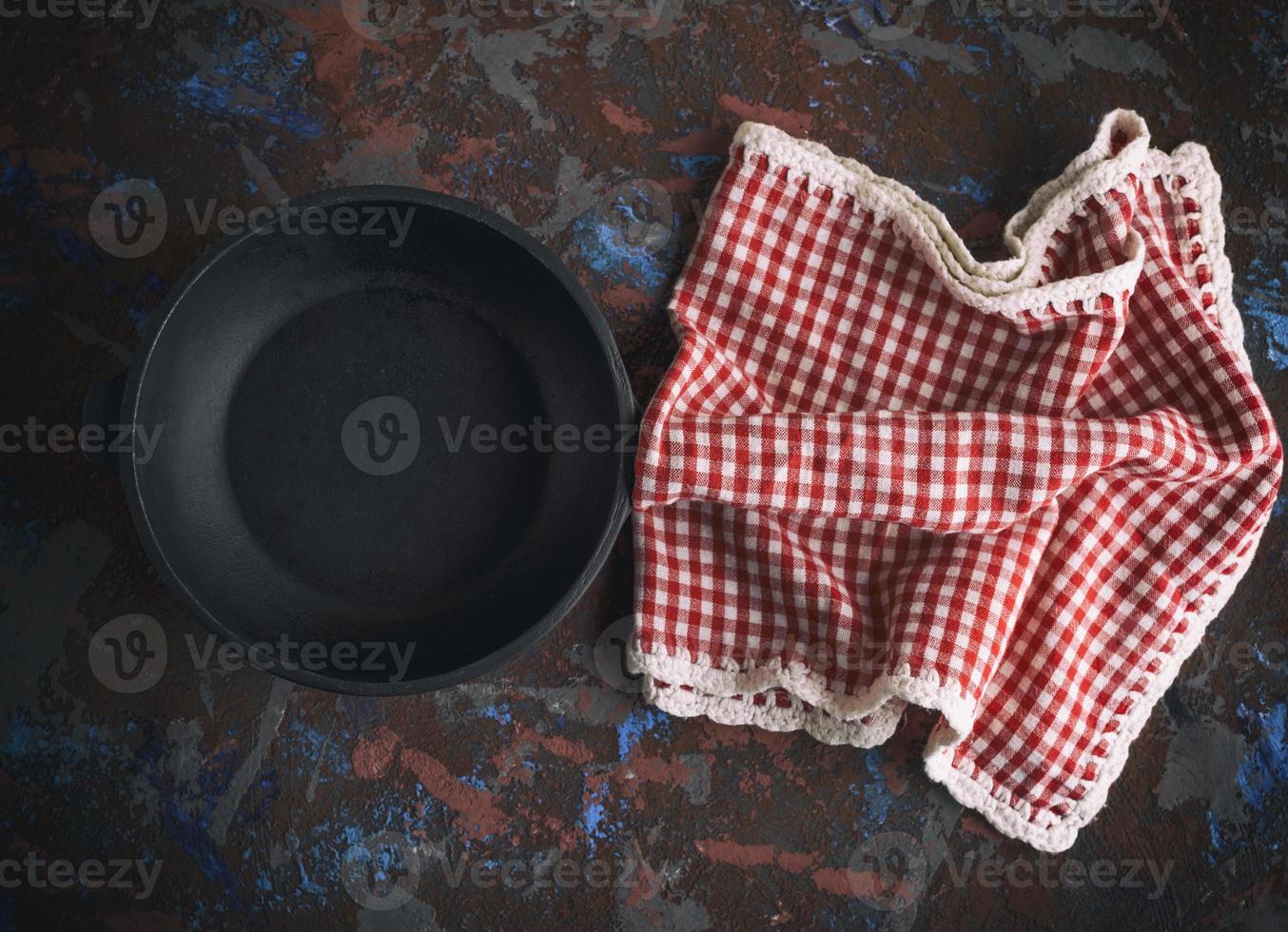 round empty black cast-iron frying pan with a red napkin in a red box photo