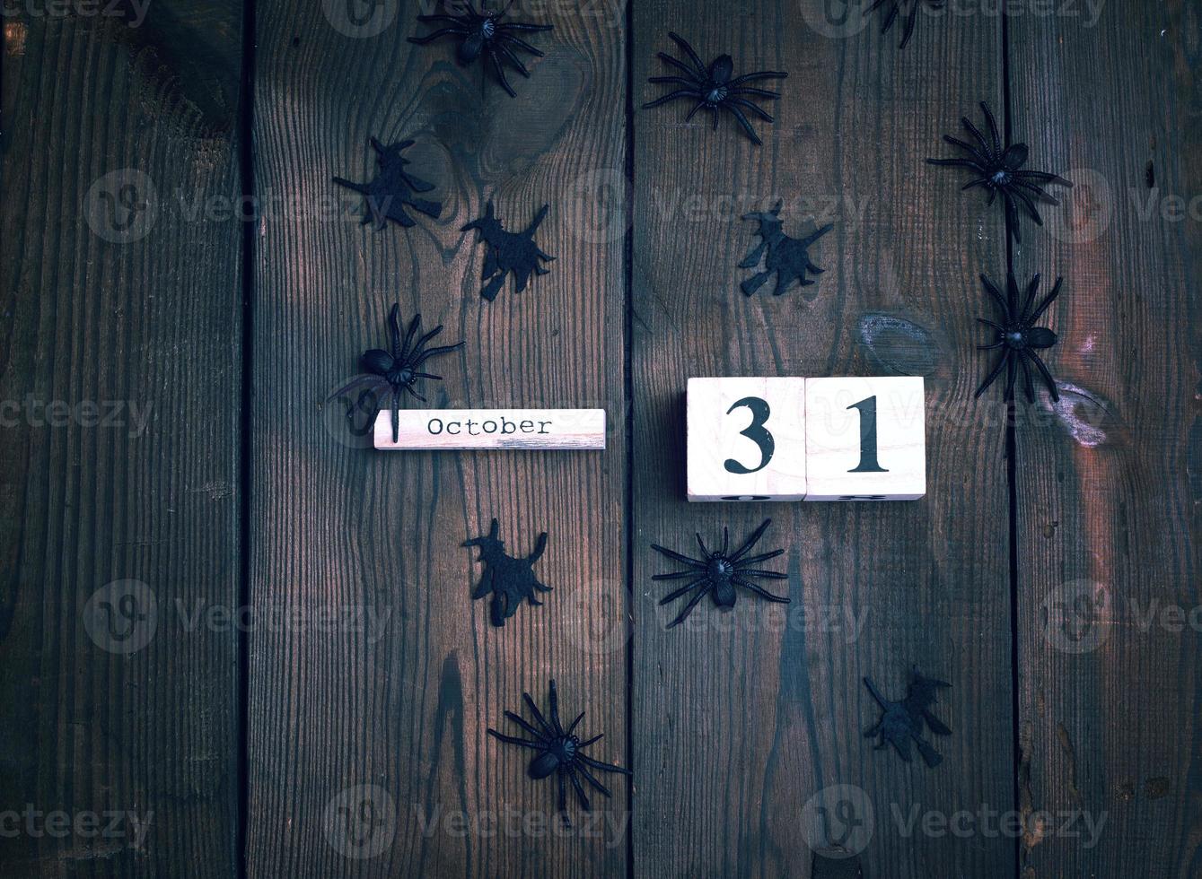 figuras de araña negra y reloj retro de madera hecho de bloques con la fecha del 31 de octubre foto