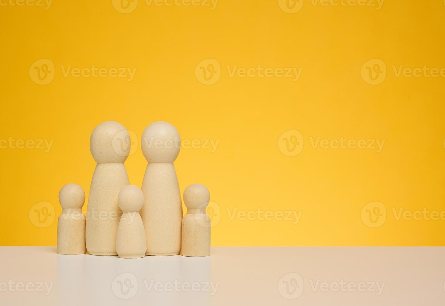 Wooden figurines of a family with children on a yellow background. The concept of protecting low-income families photo