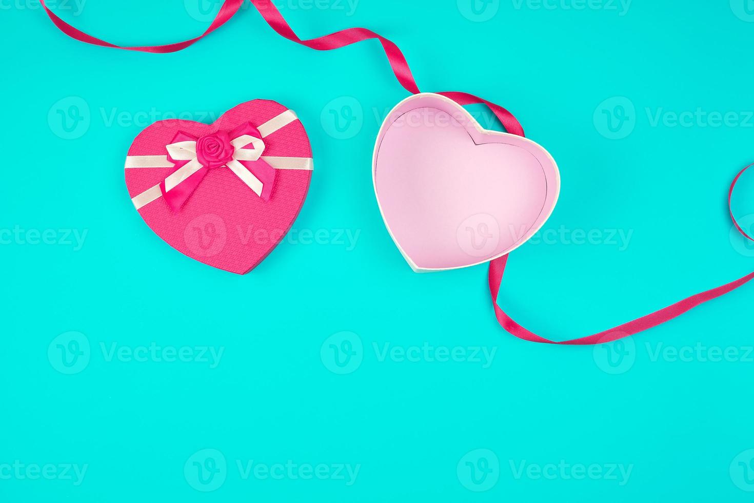 open pink heart-shaped gift box with a bow on a blue background photo