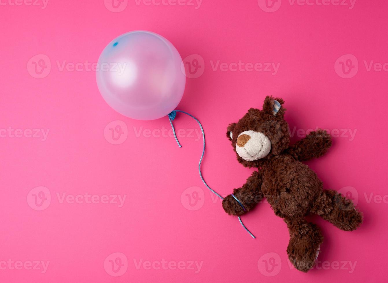 little brown teddy bear holding a blue inflated balloon photo