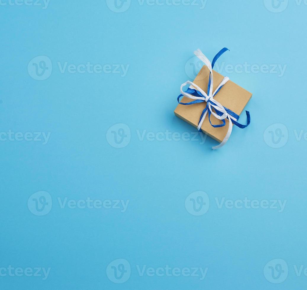 brown cardboard gift square box, bows on a blue background photo
