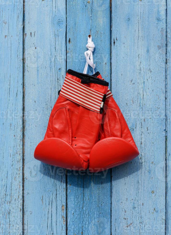 red leather boxing gloves hang on a nail photo