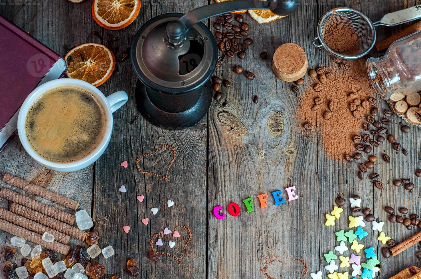 taza de café negro con dulces y especias en una superficie de madera gris foto