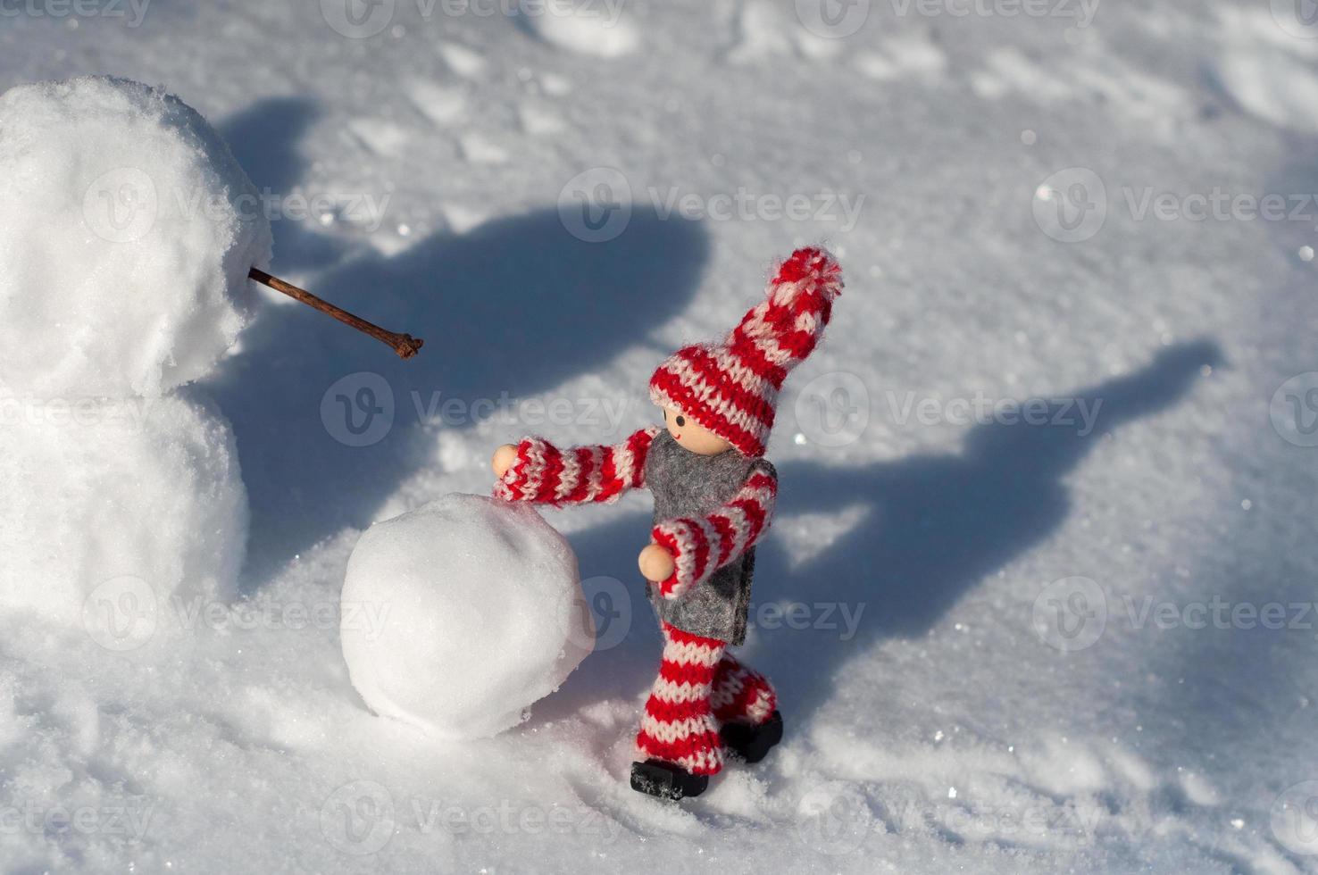 pequeño maniquí de juguete construye un muñeco de nieve foto