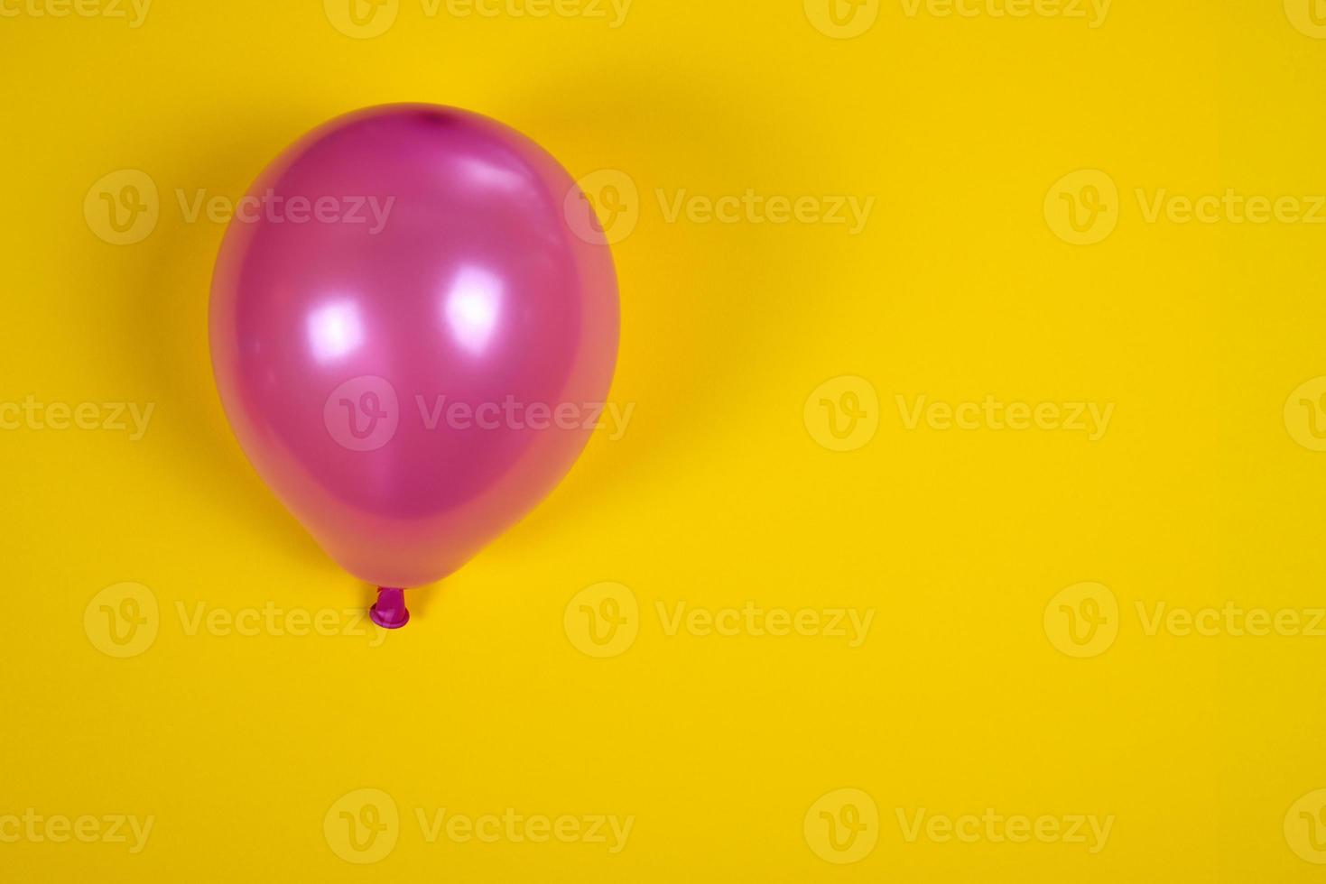 Inflated pink air balloon on the yellow surface photo