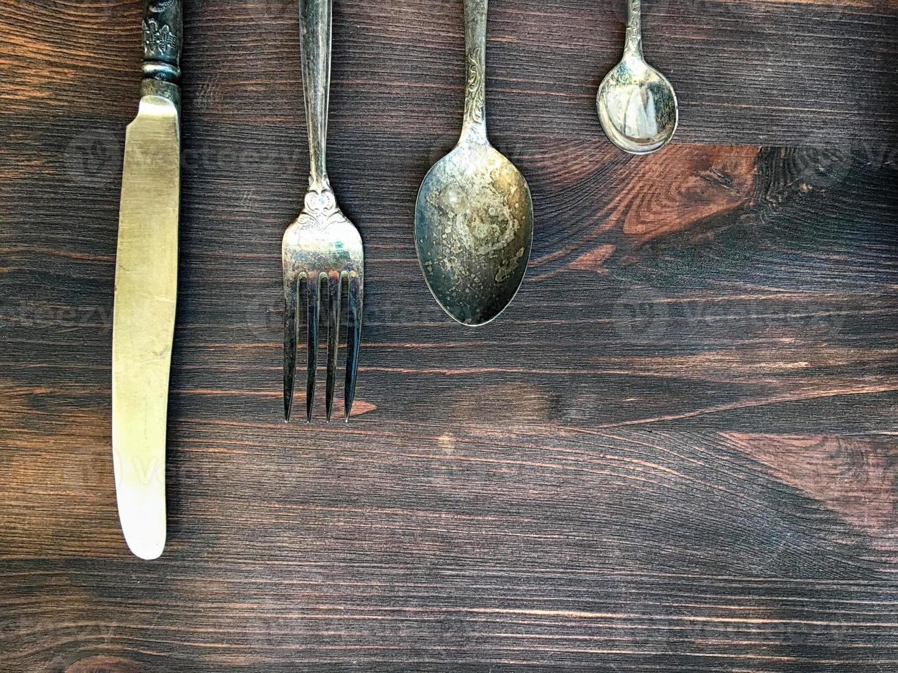 cuchillo, tenedor y cuchara sobre un fondo de madera marrón foto